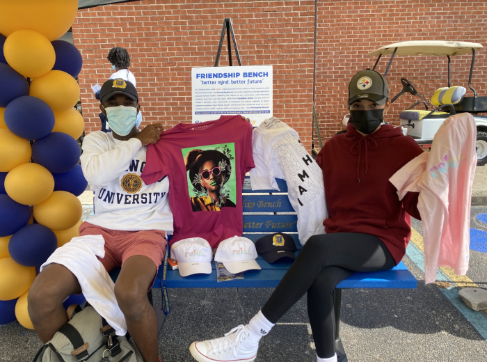 truth activists sitting on a Friendship Bench posing with some of truth's merch from the truth x Victoria Cassinova collaboration.