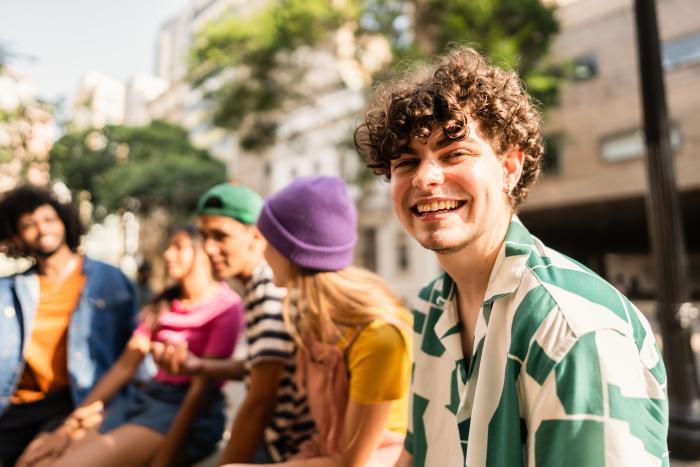 a group of people sitting together with one young man smiling to camera