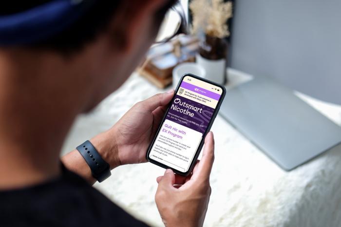 a person holding a phone looking at the outsmart nicotine page