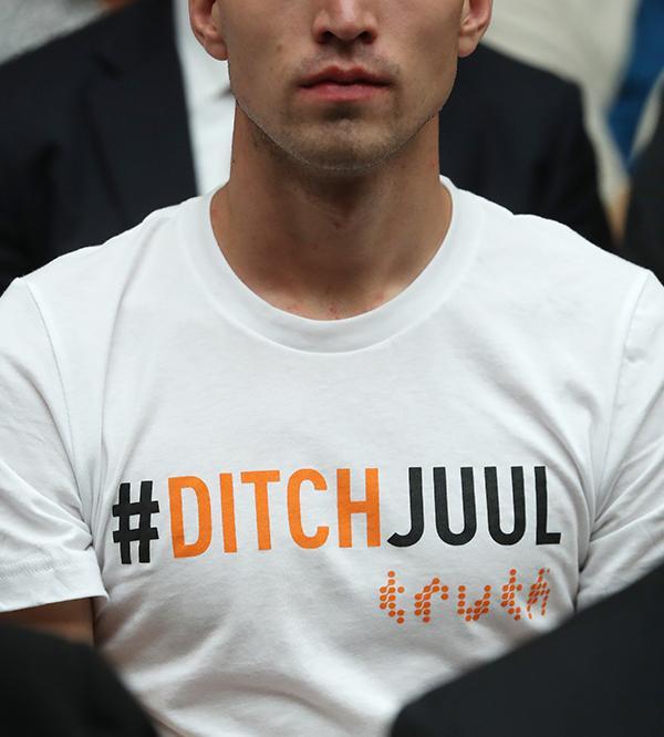 A young man in a white T-shirt reading "#DITCHJUUL" with the truth logo, seated in a crowd.